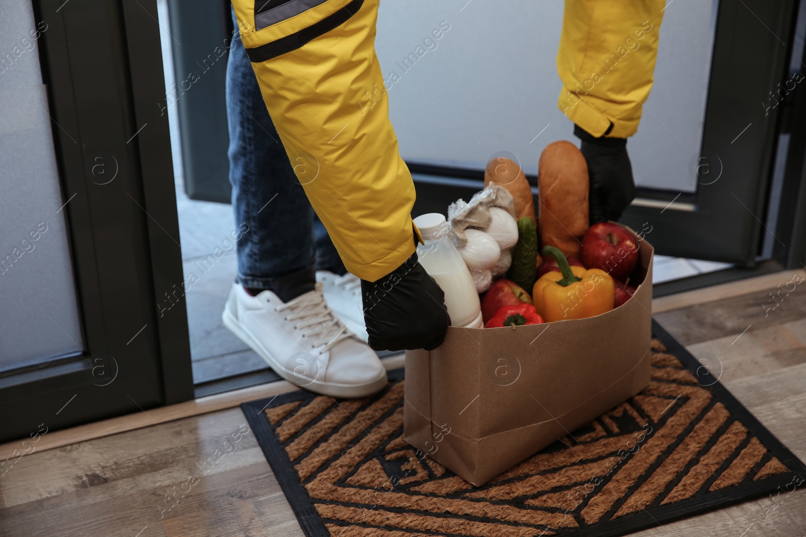 Photo of Courier bring paper bag with food to doorway, closeup. Delivery service during quarantine due Covid-19 outbreak