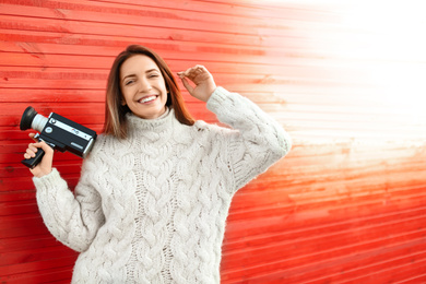Photo of Young woman with vintage video camera near red wooden wall. Space for text