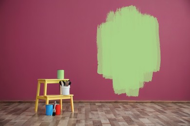 Set with decorator's tools and paint on floor near color wall