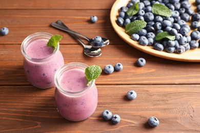 Tasty blueberry smoothie in jars and berries on wooden table