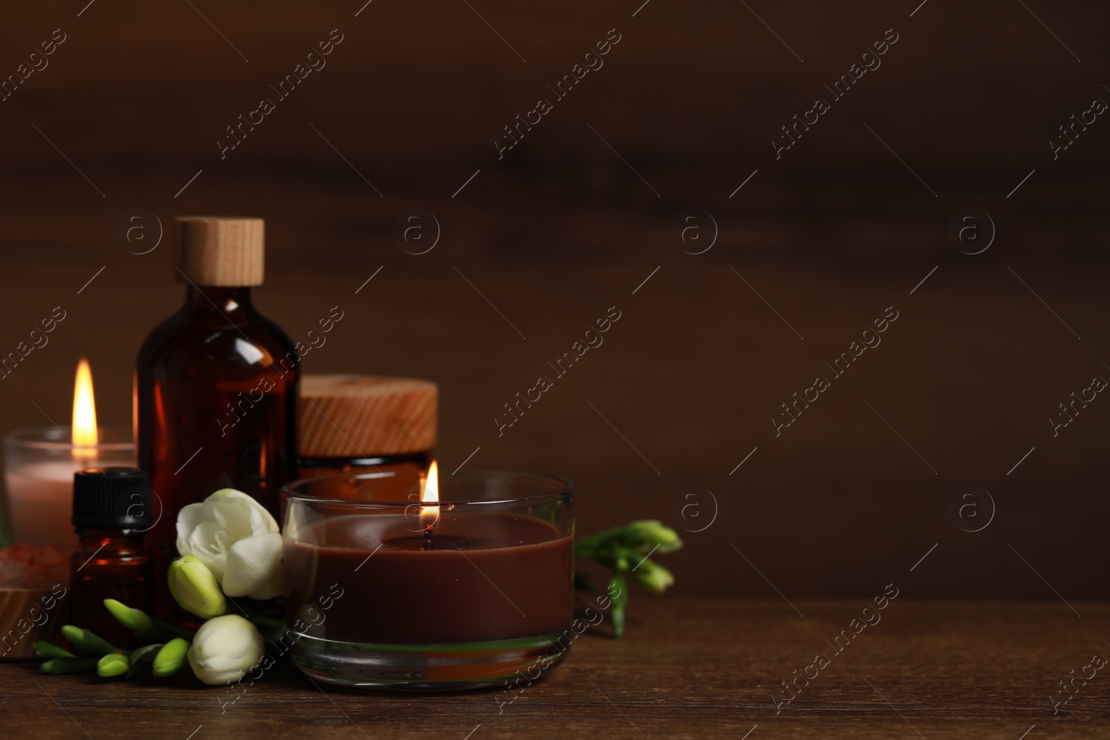 Photo of Beautiful spa composition with burning candles, different care products and flowers on wooden table. Space for text