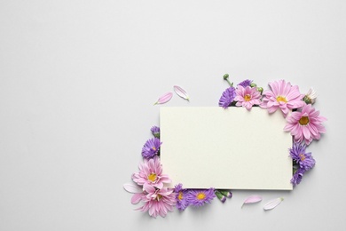 Photo of Beautiful chamomile flowers and paper card on white background, flat lay with space for text