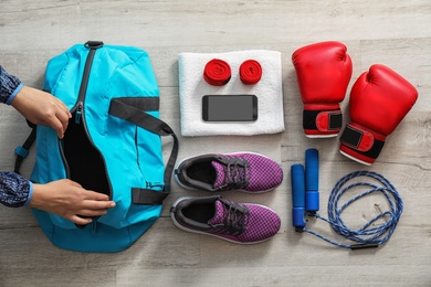 Young woman packing sports bag on floor, top view