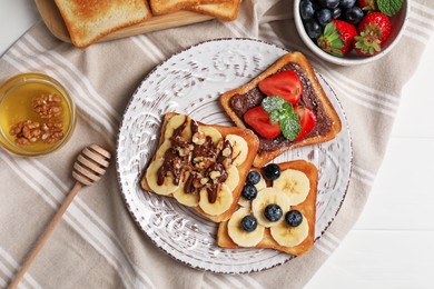Photo of Different sweet delicious toasts served on white wooden table, flat lay