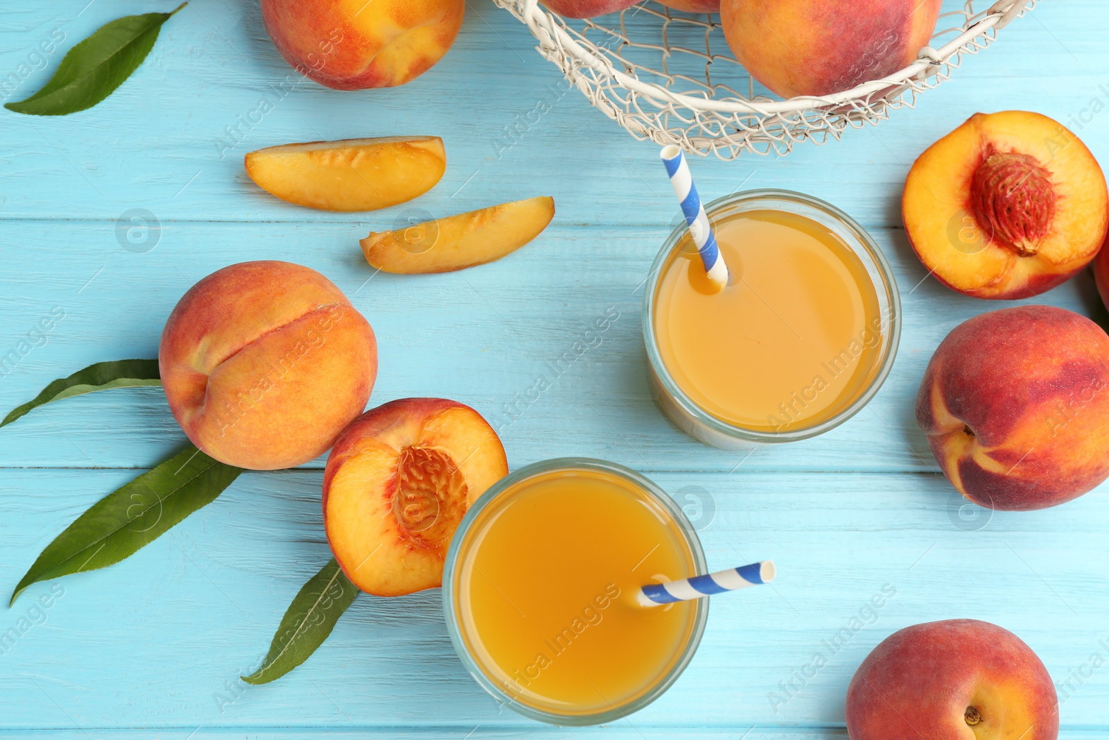 Photo of Natural peach juice and fresh fruits on light blue wooden table, flat lay