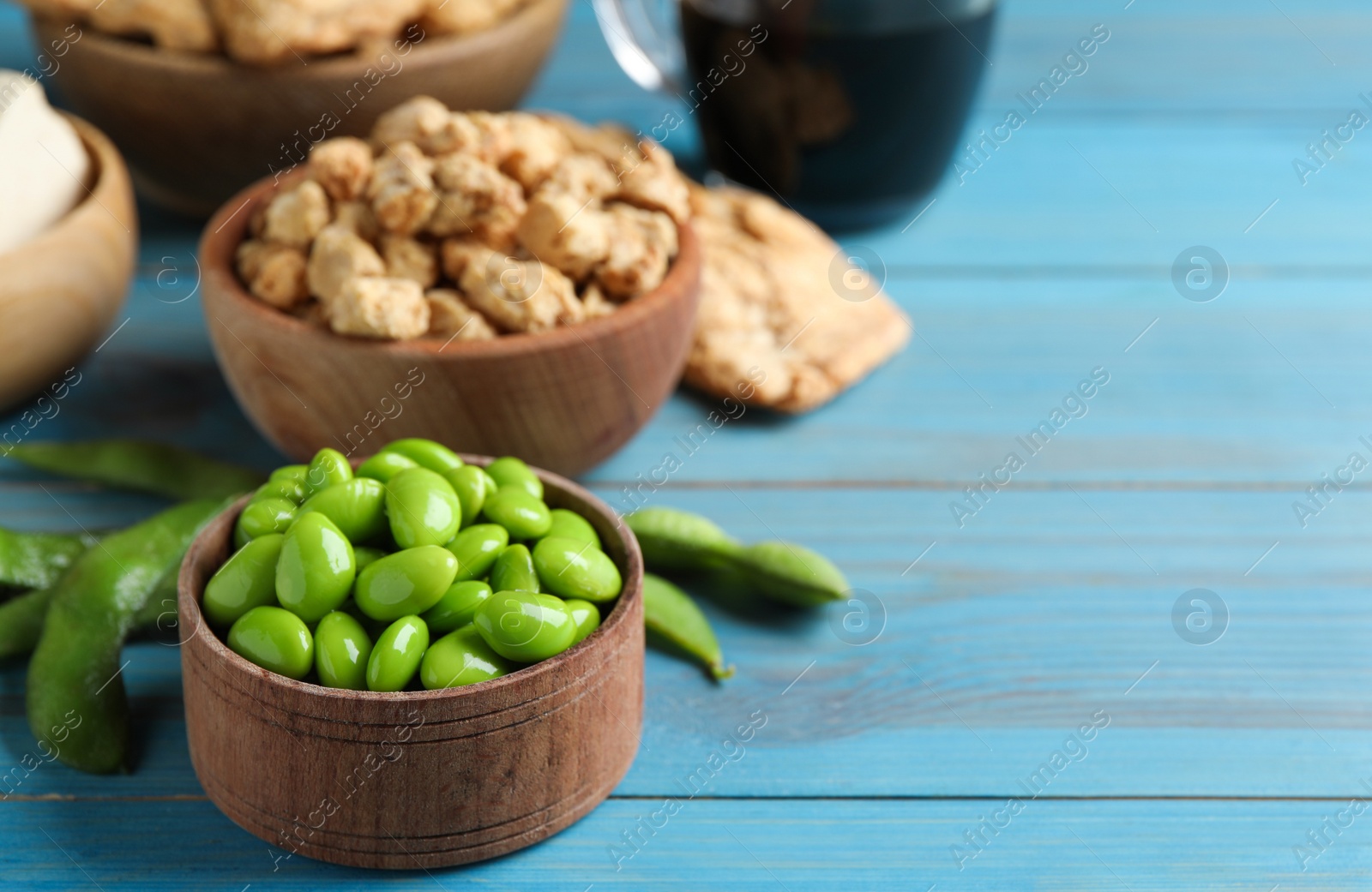 Photo of Fresh green soy beans and other organic products on light blue wooden table, closeup. Space for text