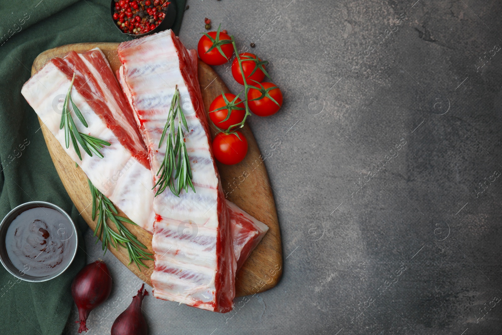 Photo of Flat lay composition with raw pork ribs and sauce on grey table. Space for text