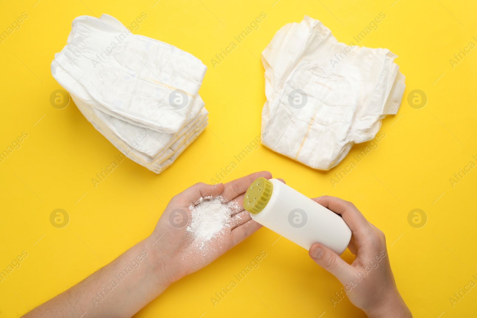 Photo of Woman applying dusting powder on yellow background, top view