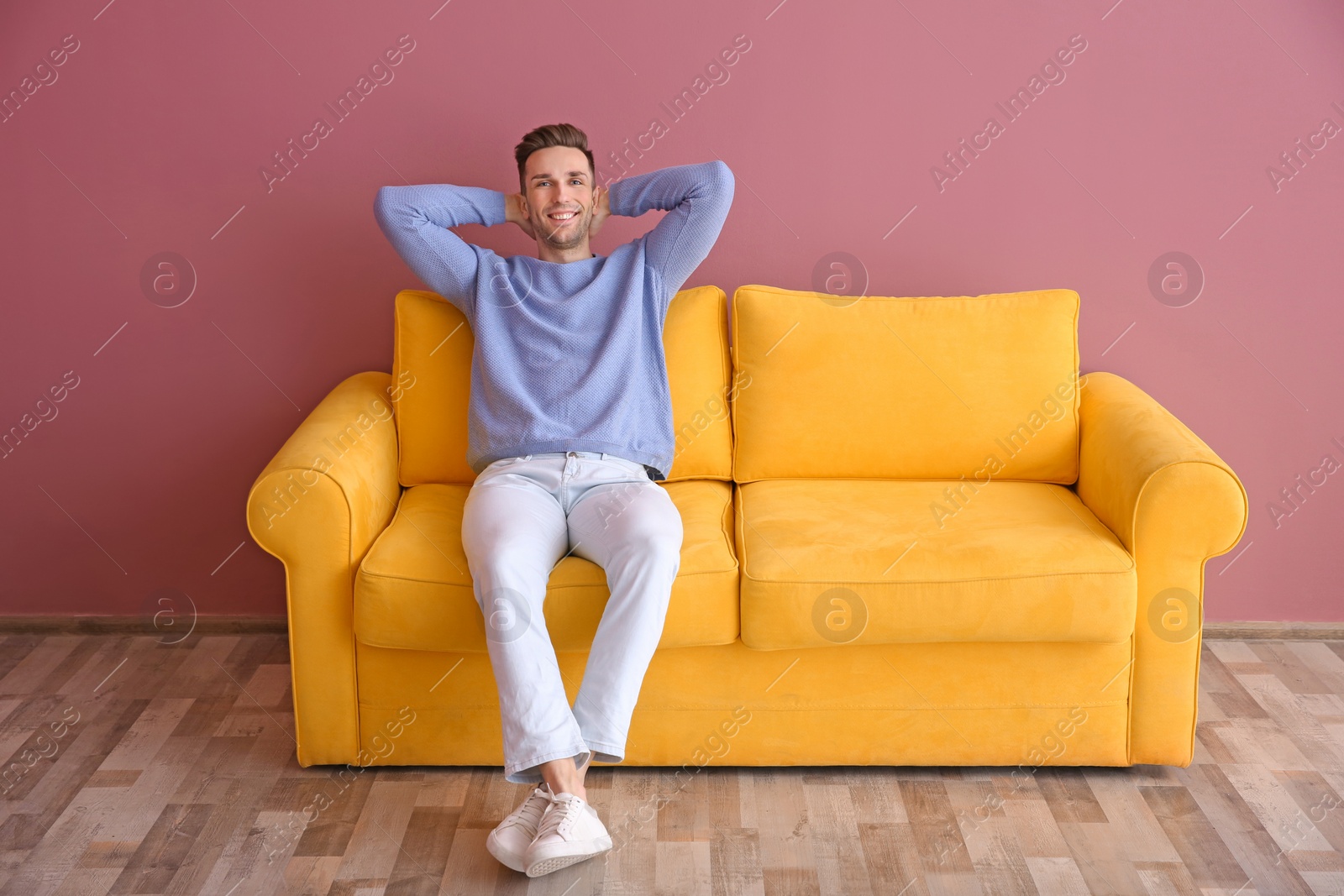 Photo of Handsome young man sitting on sofa, indoors