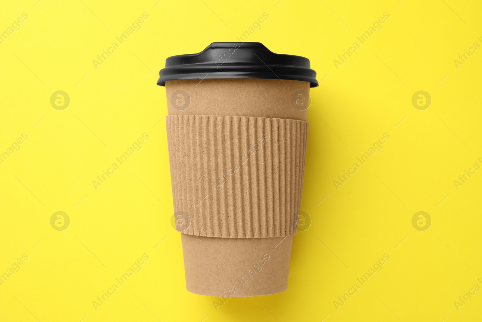 Photo of One paper cup on yellow background, top view. Coffee to go