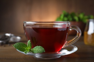 Cup of hot aromatic tea with mint on wooden table, closeup