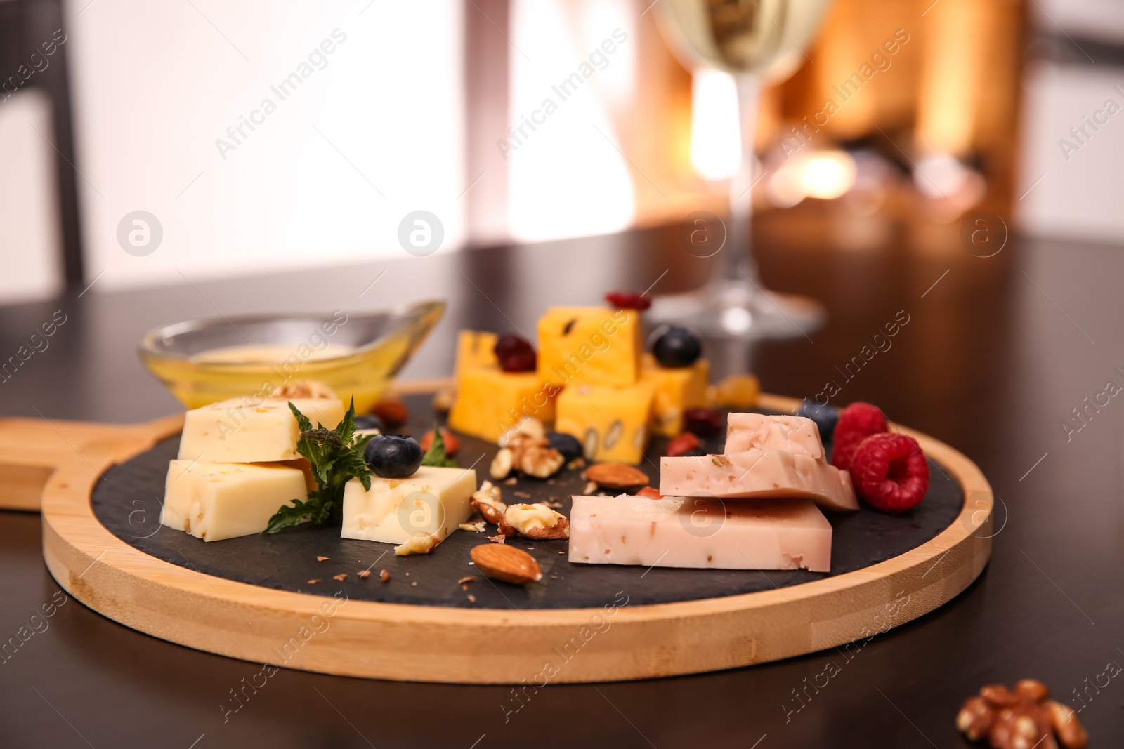 Photo of Different types of delicious cheeses, berries and honey on table