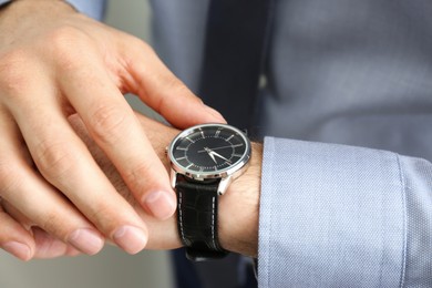 Photo of Man wearing luxury wrist watch with leather band, closeup