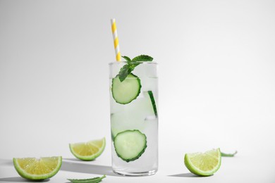 Photo of Glass of tasty fresh cucumber water with mint and sliced lime on white background