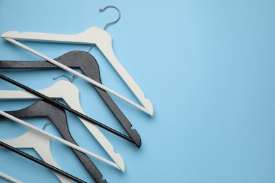 Empty clothes hangers on light blue background, flat lay. Space for text