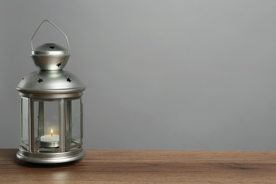 Decorative Christmas lantern with burning candle on grey background. Space for text