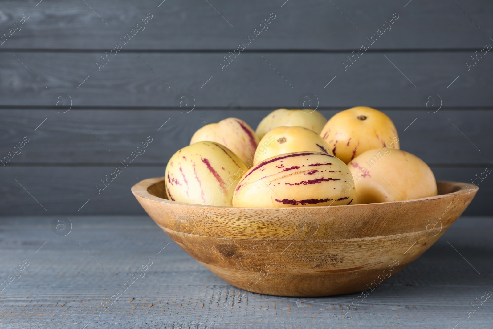 Photo of Fresh ripe pepino melons on grey wooden table