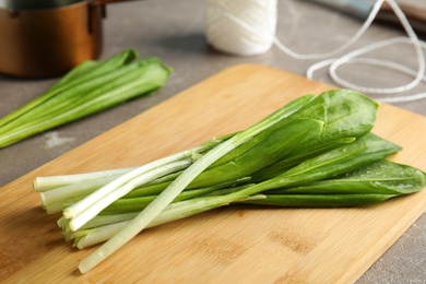 Photo of Board with wild garlic or ramson on grey table, closeup