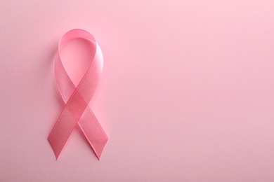 Pink ribbon on color background, top view with space for text. Breast cancer awareness concept