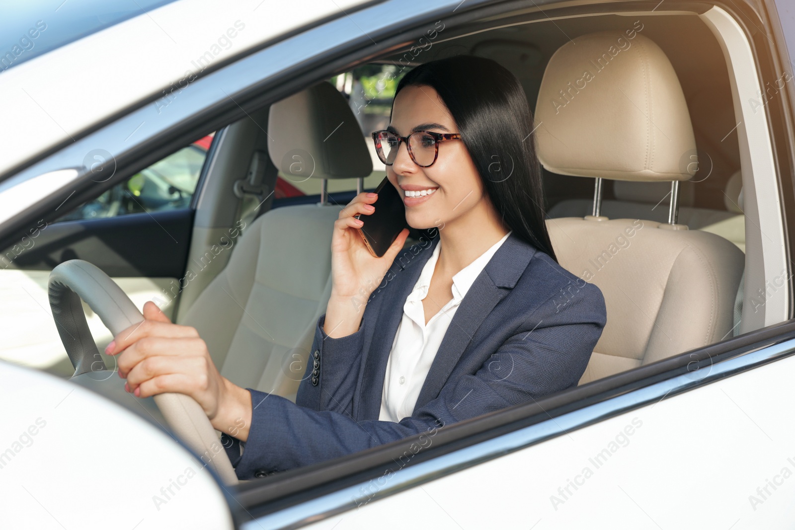 Photo of Beautiful young driver talking on phone in modern car