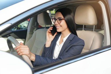 Photo of Beautiful young driver talking on phone in modern car