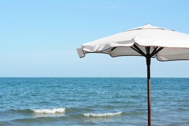 Photo of Beautiful white beach umbrella near sea on sunny day, space for text