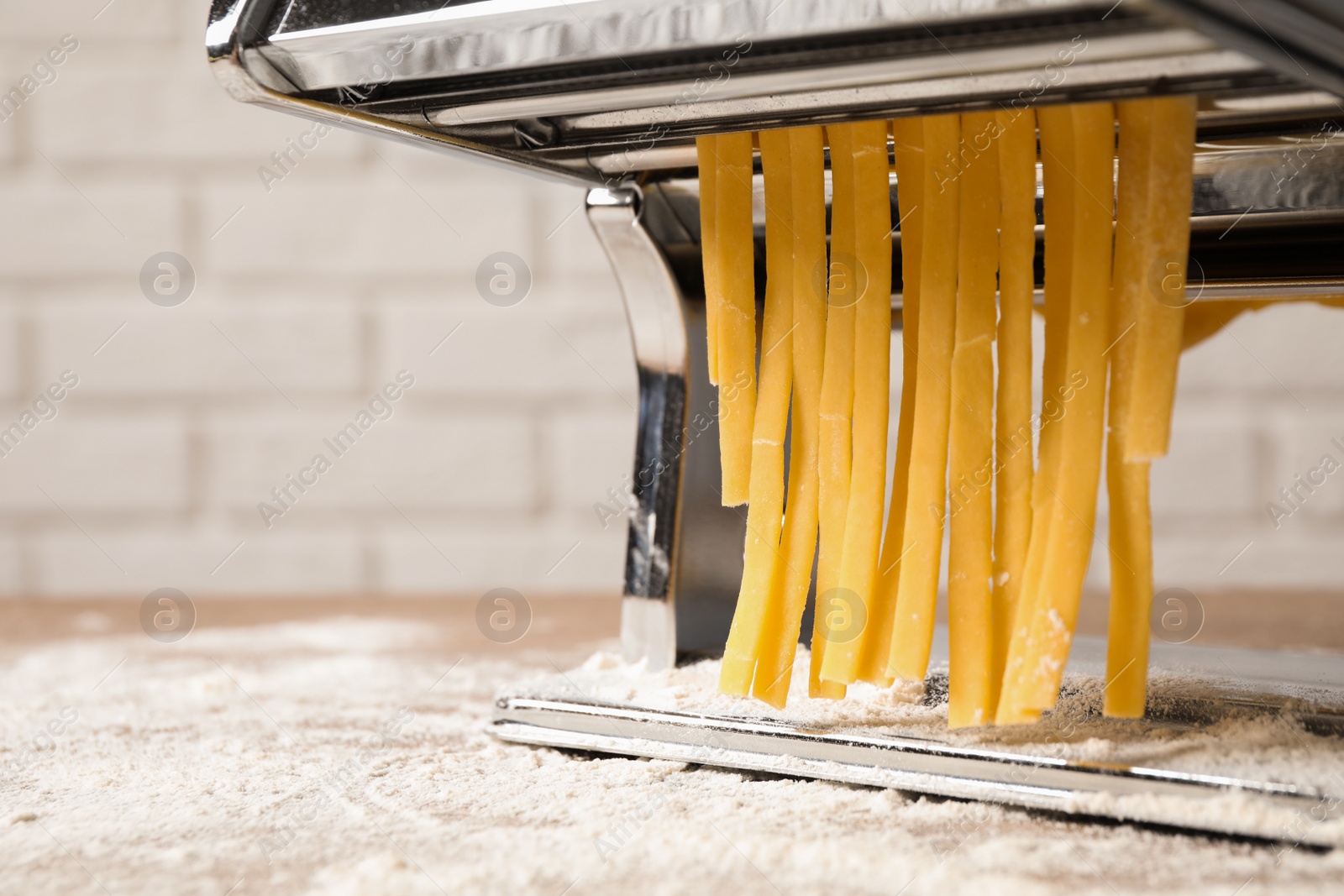 Photo of Pasta maker machine with dough on table, closeup