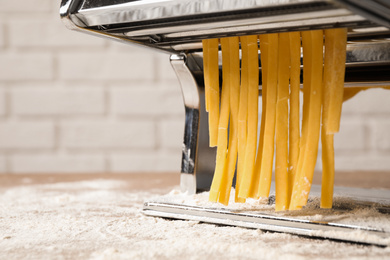 Pasta maker machine with dough on table, closeup