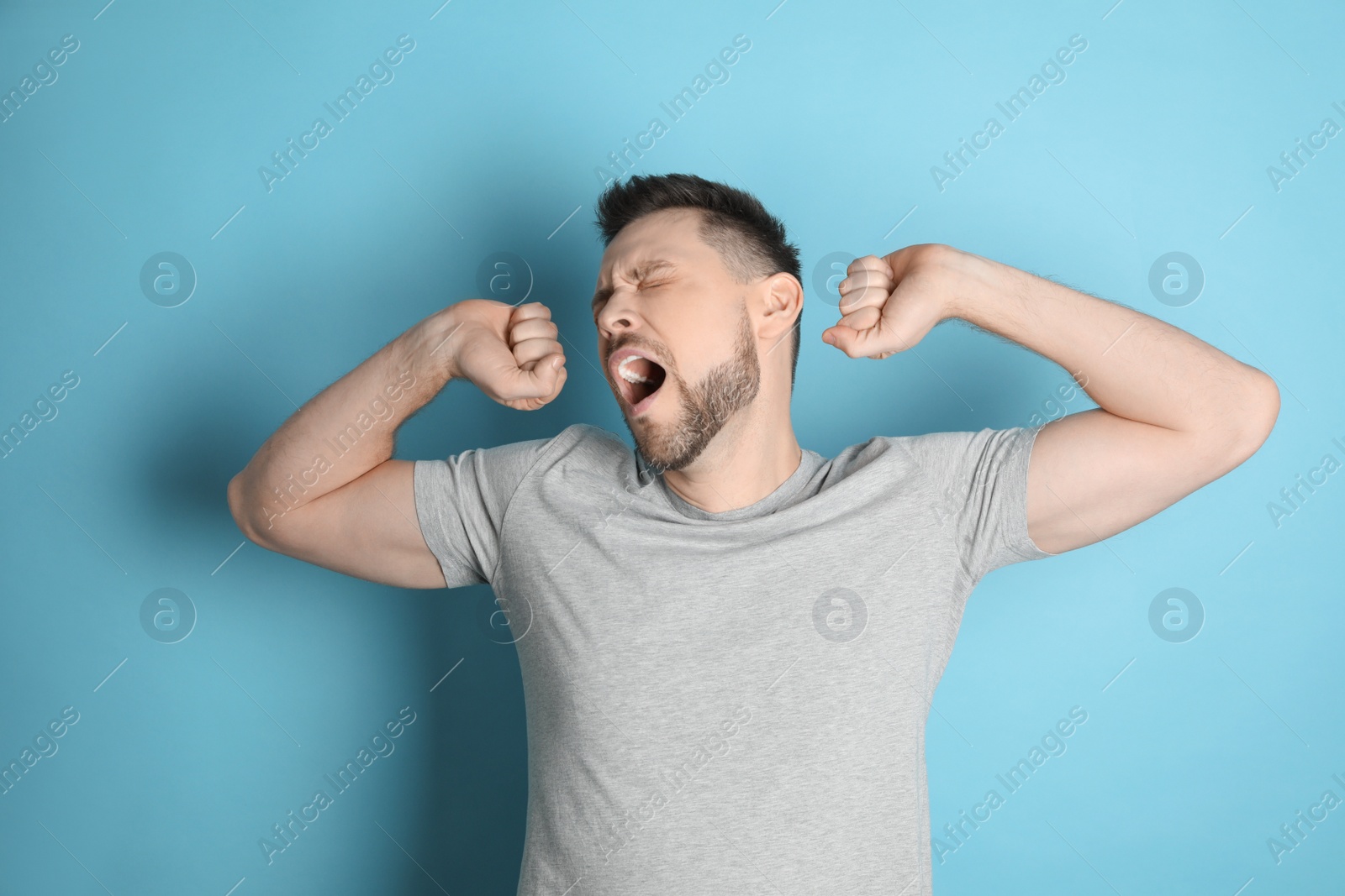 Photo of Portrait of sleepy man yawning on turquoise background