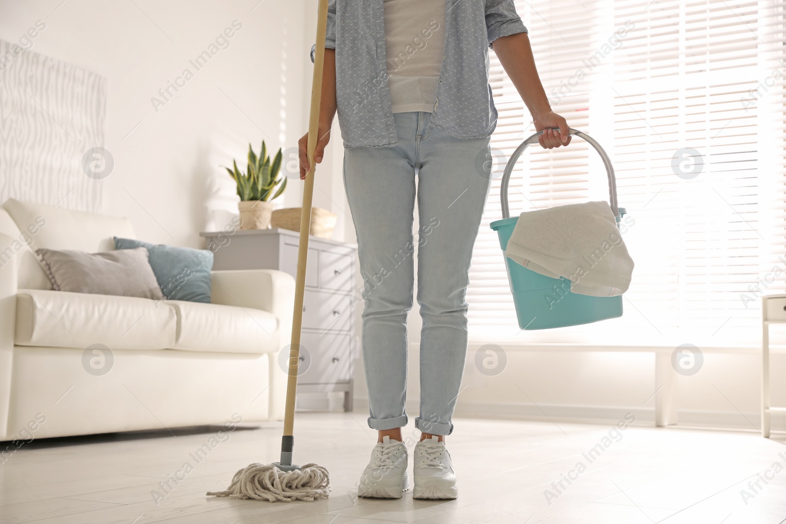 Photo of Woman with mop and bucket in room, closeup. Cleaning supplies