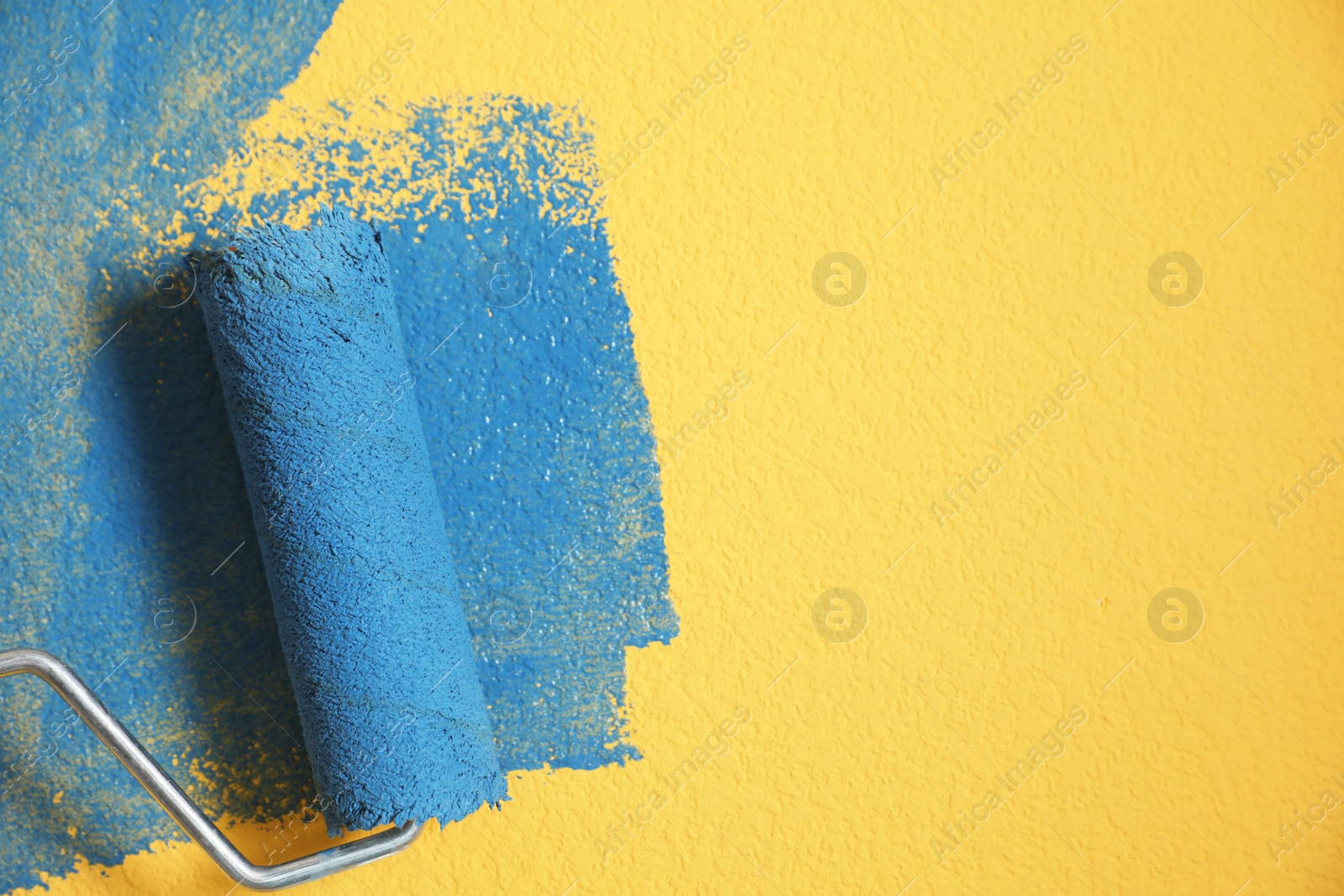 Photo of Painting yellow wall with blue dye, closeup view. Space for text