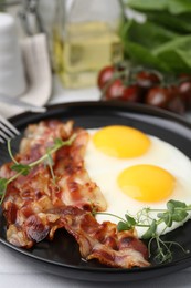 Fried eggs, bacon and microgreens on table