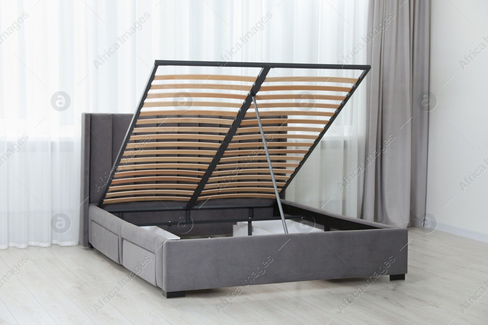 Photo of Modern bed with storage space for bedding under lifted slatted base in room