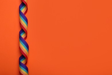 Photo of Rainbow ribbon on orange background, top view with space for text. LGBT pride