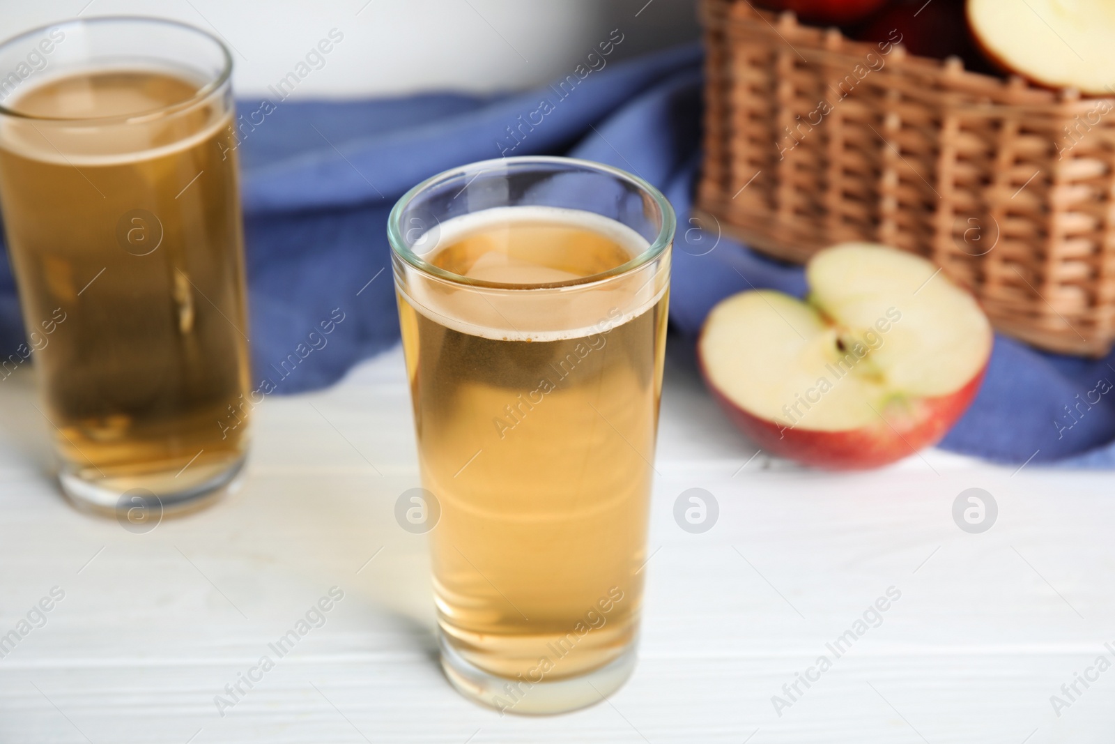 Photo of Glasses of delicious apple cider on white table