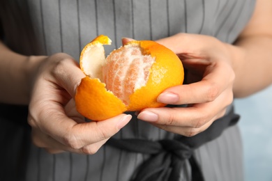 Photo of Woman peeling ripe tangerine, closeup. Citrus fruit