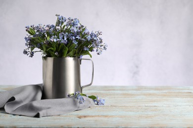 Photo of Beautiful forget-me-not flowers and napkin on wooden rustic table against light background, closeup. Space for text