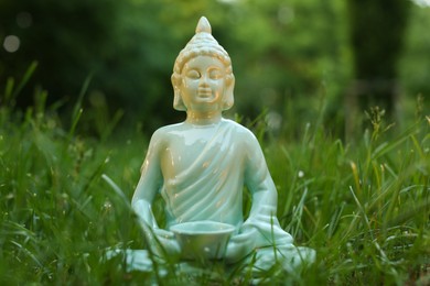 Photo of Decorative Buddha statue in green grass outdoors