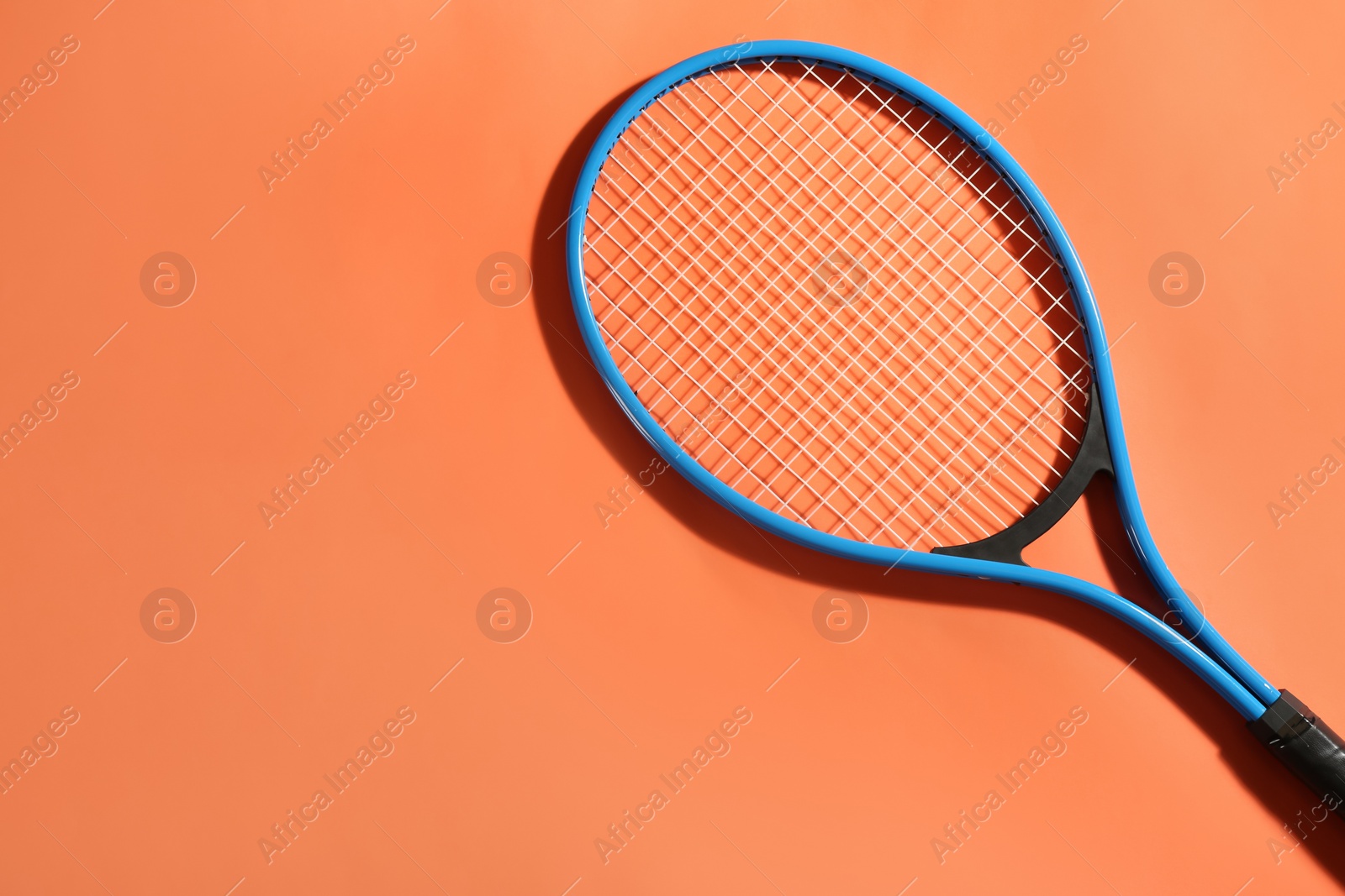 Photo of Tennis racket on orange background, top view. Space for text