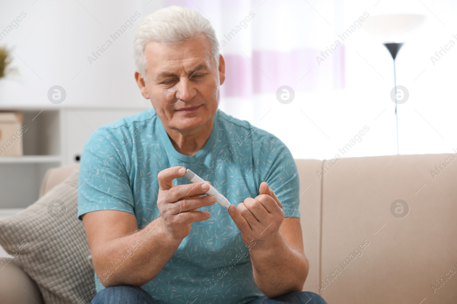 Photo of Senior man using lancet pen at home. Diabetes control