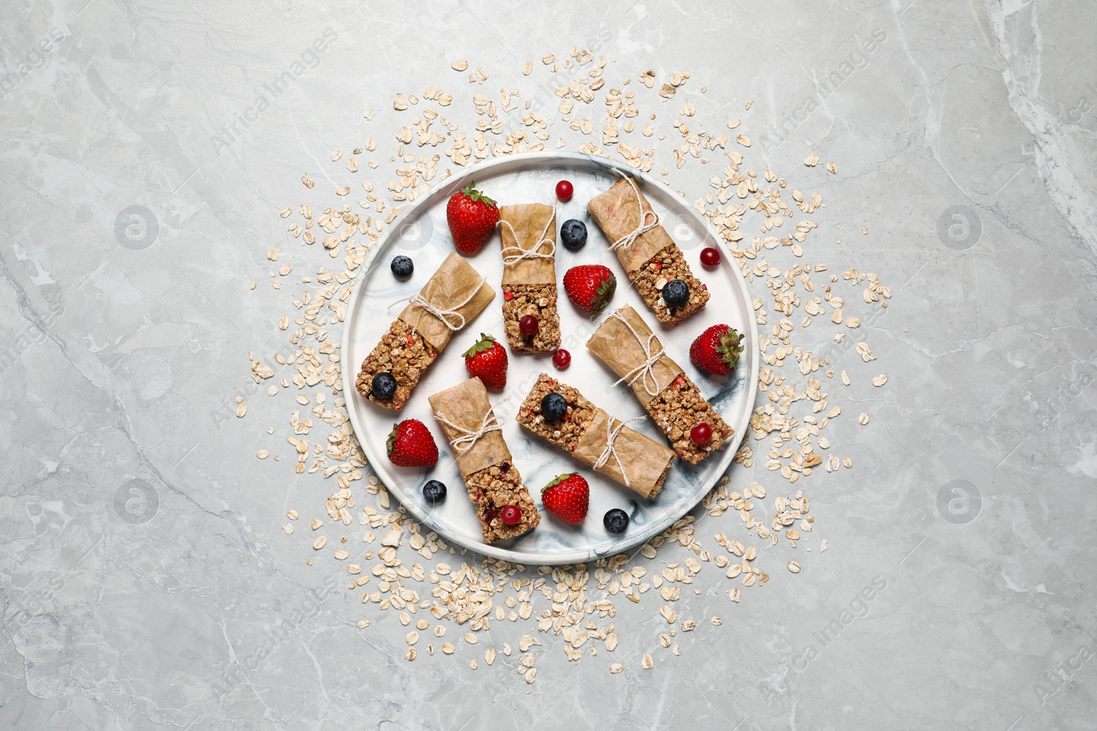 Photo of Tasty granola bars and ingredients on light grey table, top view
