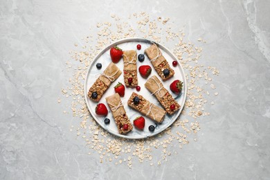 Tasty granola bars and ingredients on light grey table, top view