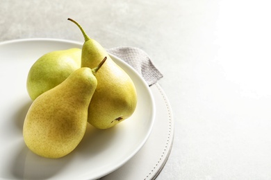 Photo of Plate with ripe pears on light background. Space for text