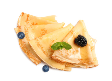 Delicious thin pancakes with berries on white background, top view