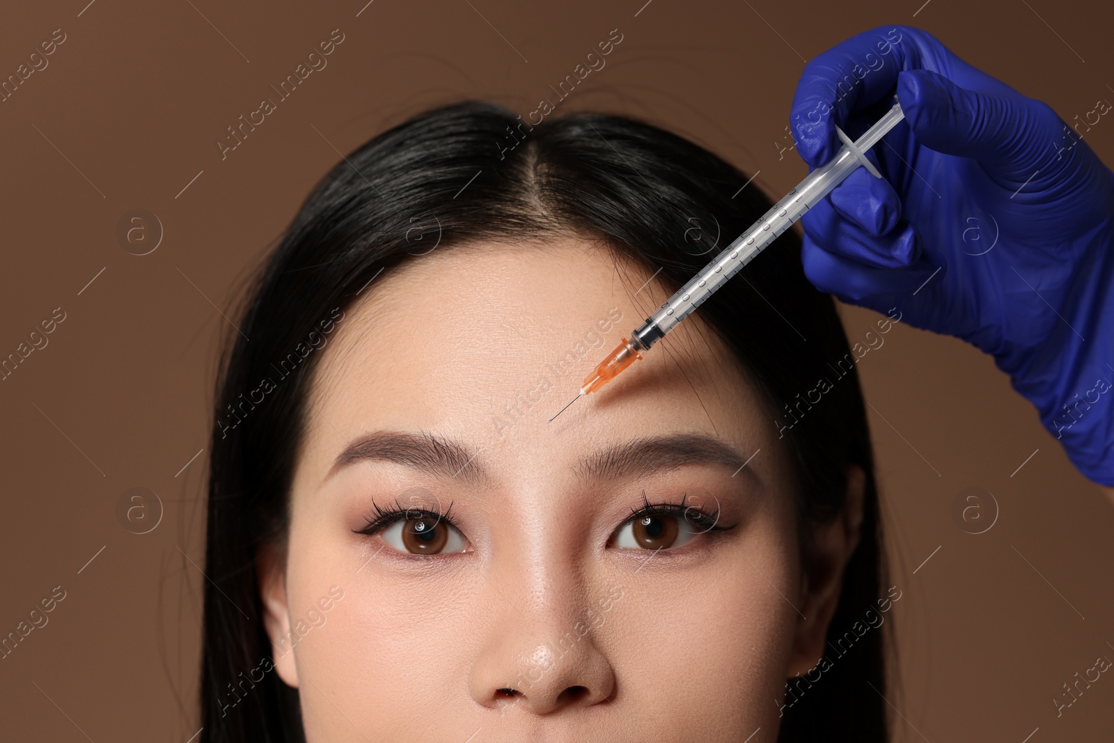 Photo of Woman getting facial injection on brown background, closeup