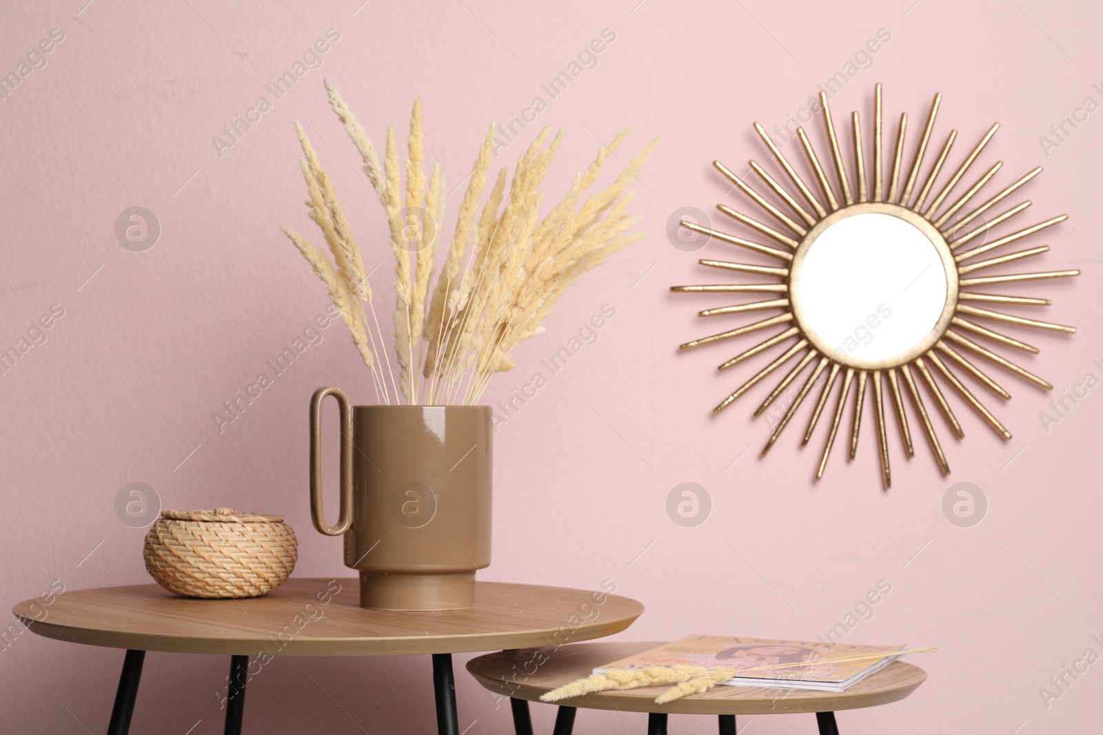 Photo of Stylish ceramic vase with dry flowers on wooden table near pink wall