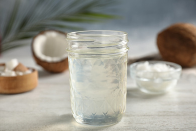 Photo of Coconut oil on white wooden table, closeup