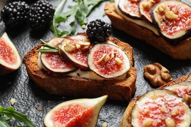 Photo of Bruschettas with cream cheese, figs and blackberries on slate plate, closeup