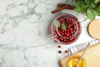 Flat lay composition with tasty hot cranberry tea and fresh ingredients on white marble table. Space for text