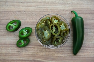 Fresh and pickled green jalapeno peppers on wooden table, flat lay